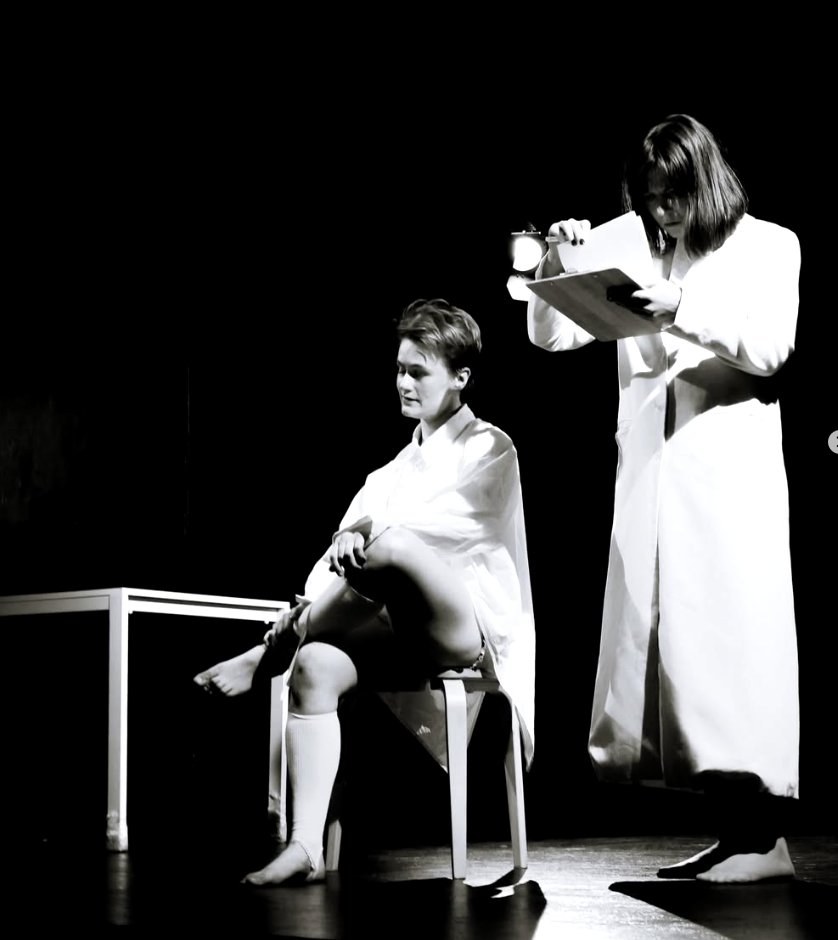 A figure on a stool, another with a clipboard above her