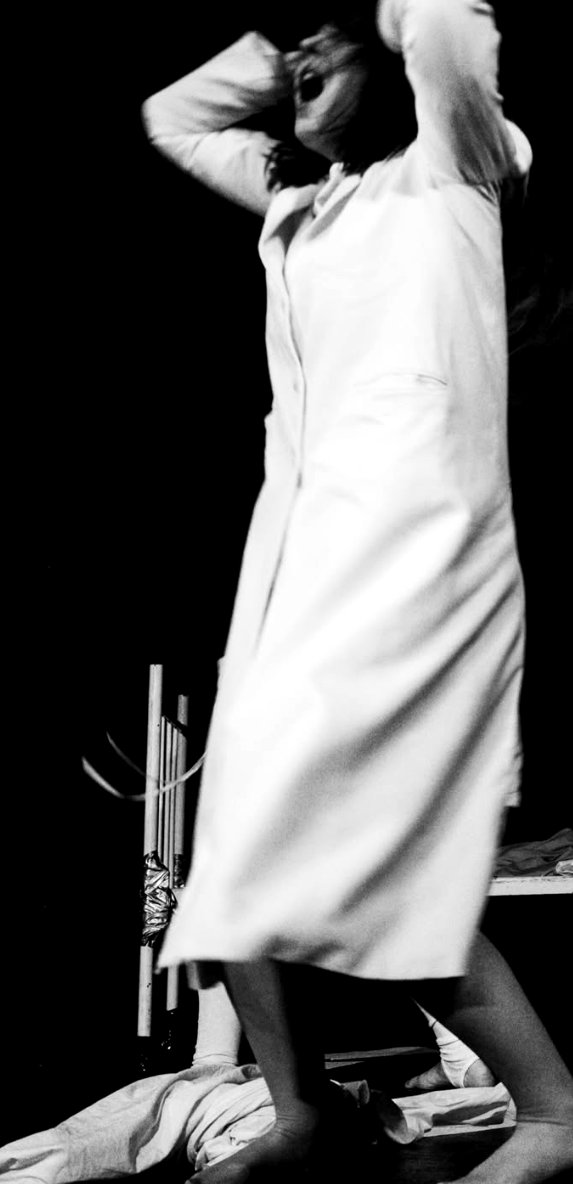 A blurred figure in white, hands raised to head