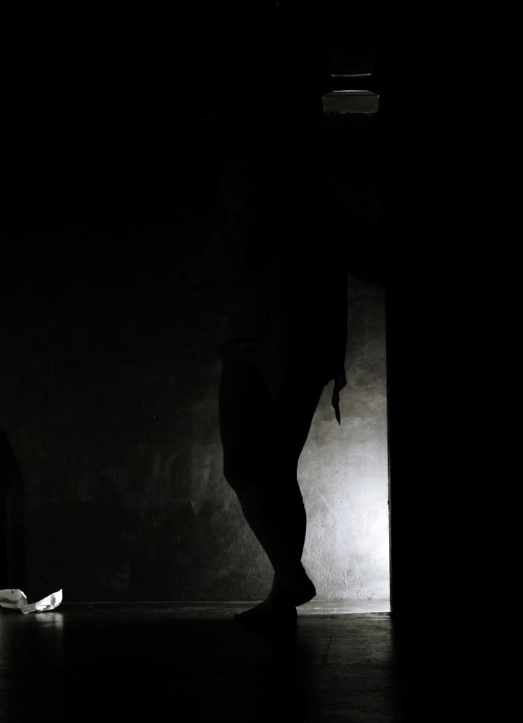 A silhouette in a doorway, lit from above
